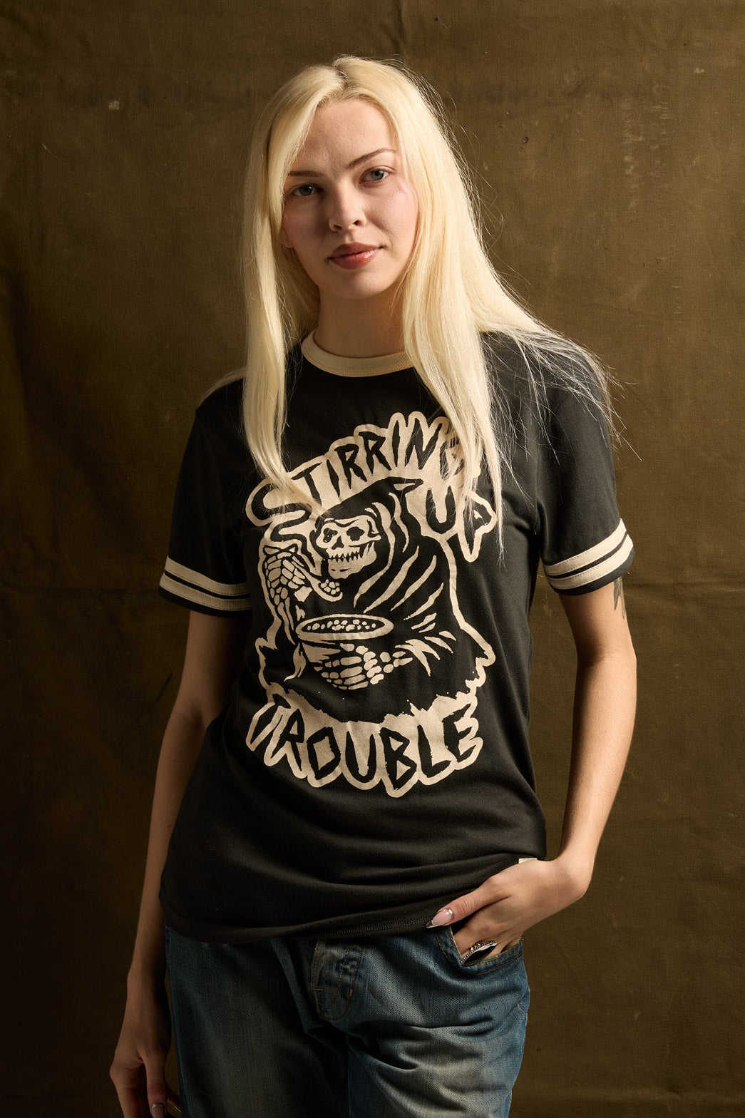 Person wearing a black t-shirt with graphic design against a brown backdrop