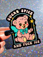 Die-cut holographic glitter vinyl sticker on a black background featuring a retro kawaii bear with a teal bow and stars. Arched text at top reads Sugar Spice and text at bottom reads And Fuck ICE.