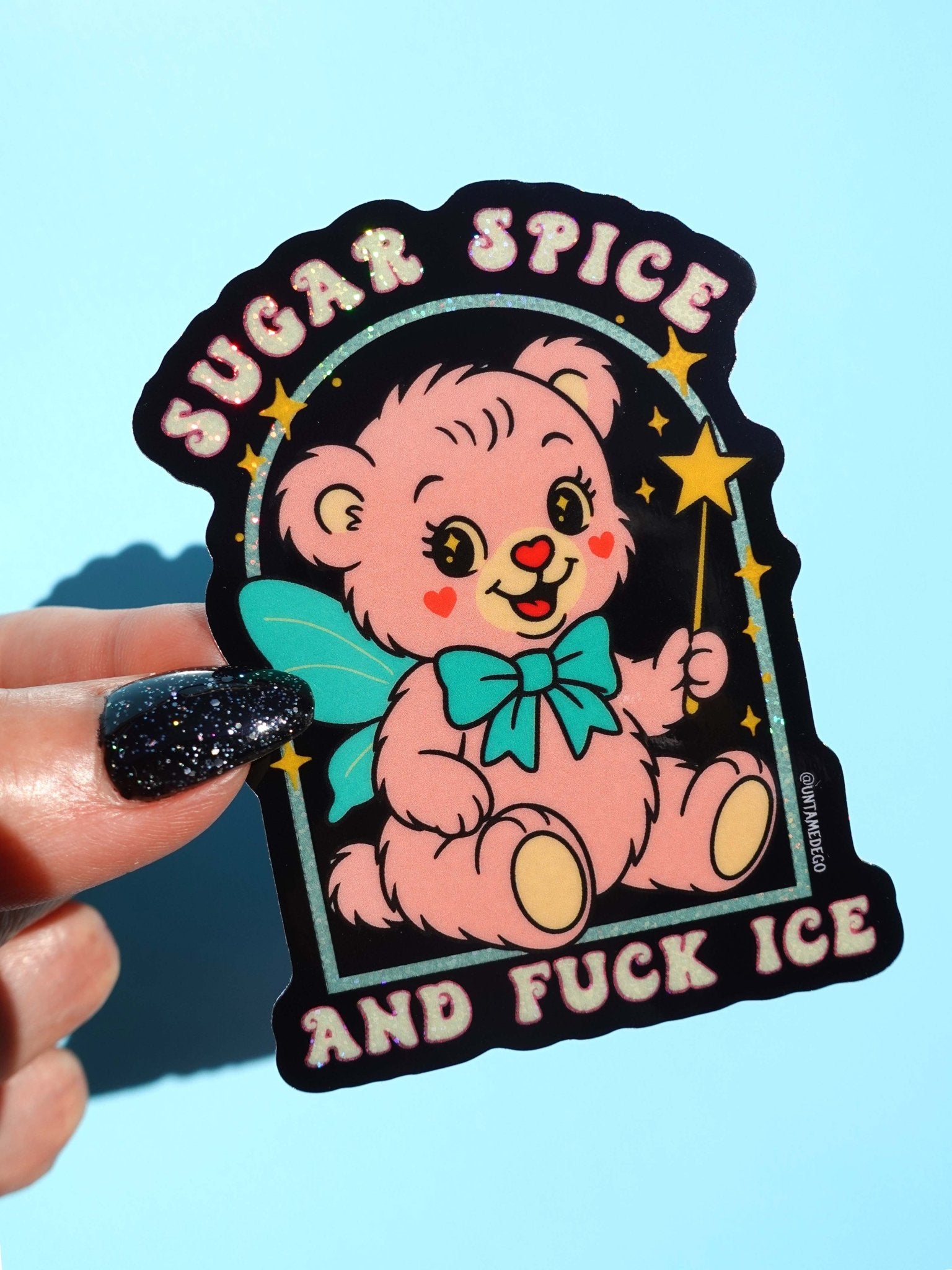 Die-cut holographic glitter vinyl sticker on a black background featuring a retro kawaii bear with a teal bow and stars. Arched text at top reads Sugar Spice, and text at bottom reads And Fuck ICE.