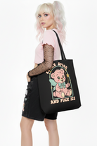 Person holding a black tote bag with a graphic design and text.