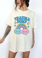 Funny graphic t-shirt with rainbow and crying clouds design and text saying trauma dump