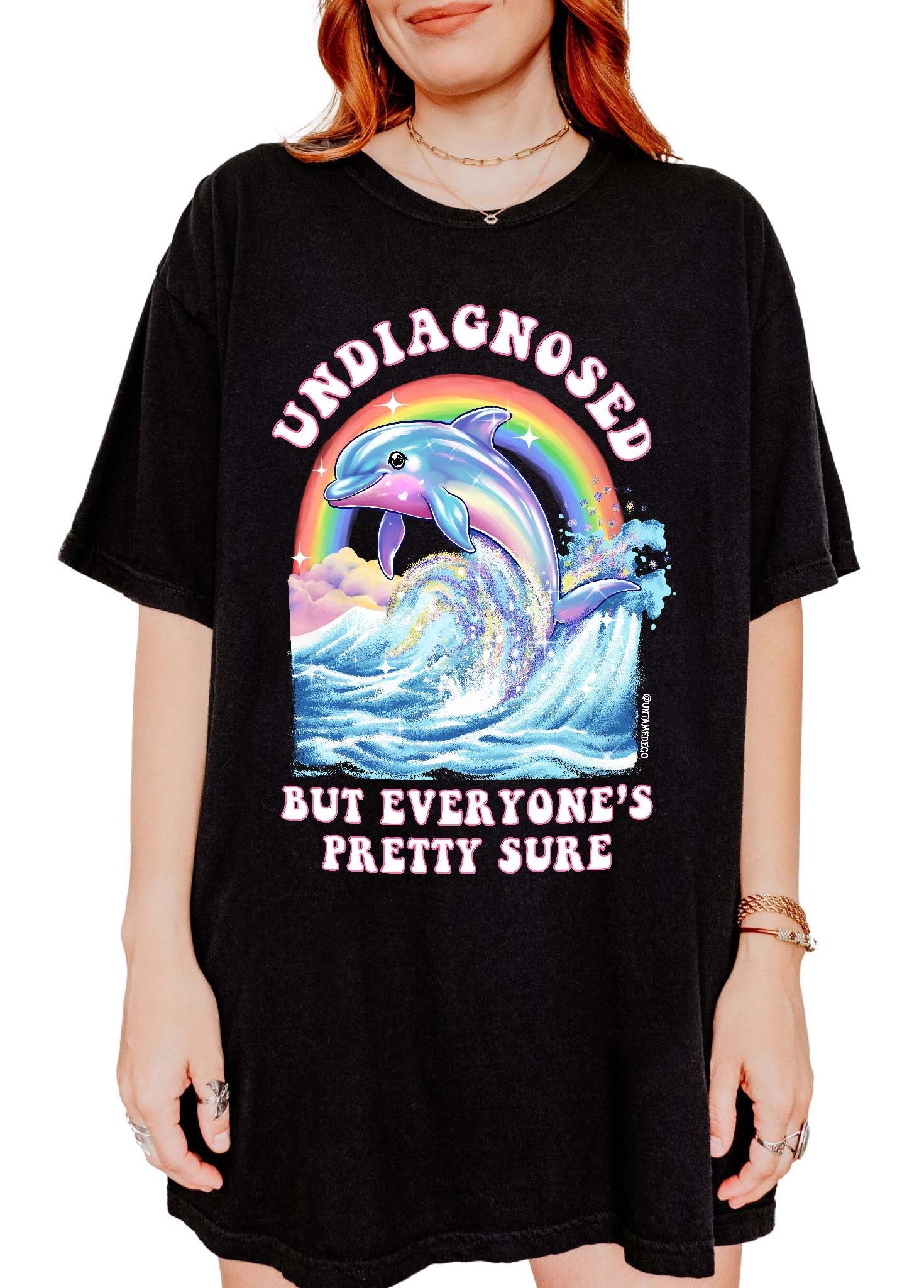 Funny graphic t-shirt with dolphin and rainbow design and text saying undiagnosed but everyone’s pretty sure