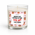 A clear glass jar candle with white wax and a printed front label. The label features a pink background with cartoon reindeer faces and the text 'BEING MY SISTER IS THE only gift YOU NEED' in black and red lettering.