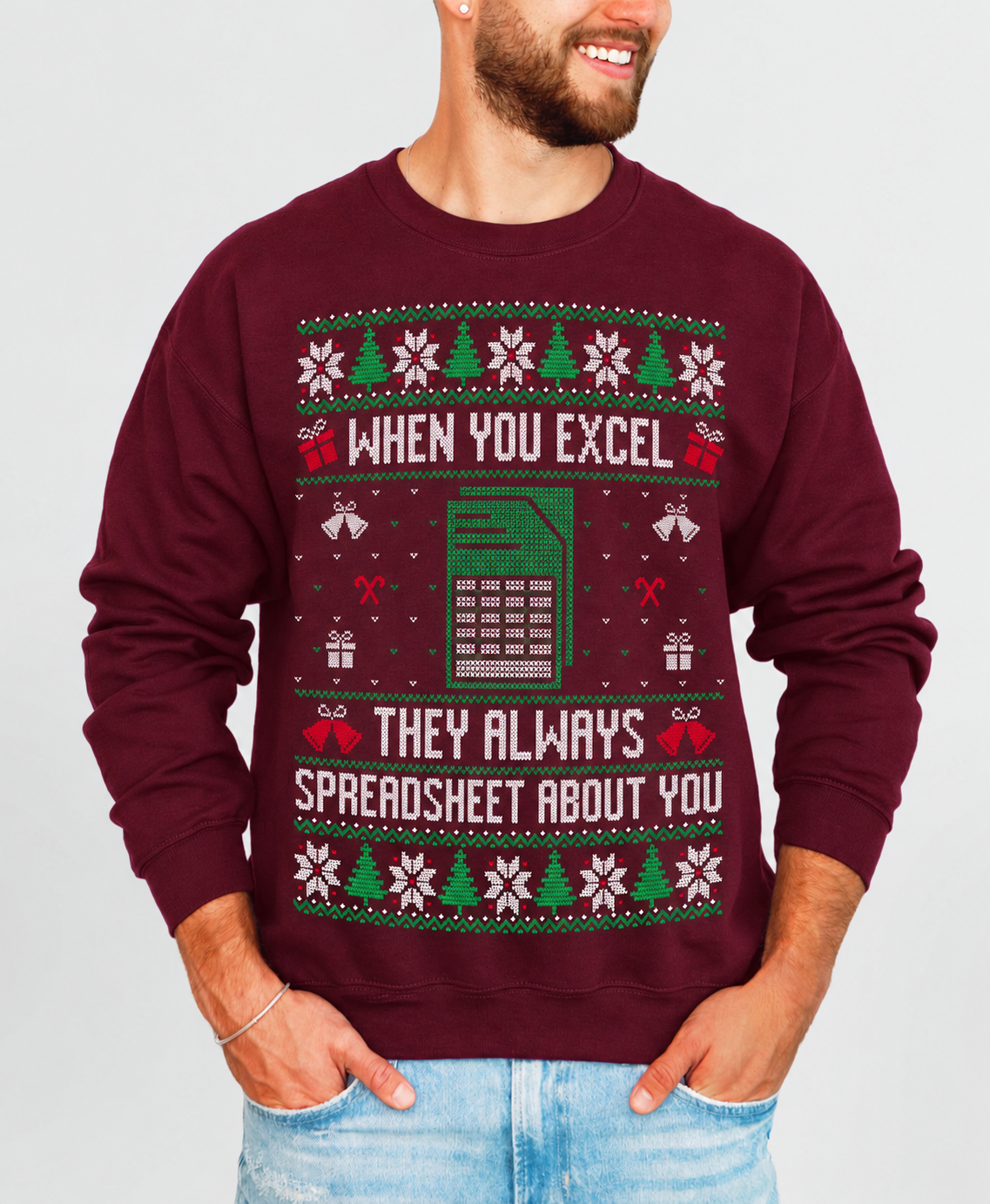 A man wearing a maroon crewneck sweatshirt with a festive Christmas-themed spreadsheet joke graphic. The graphic features green and white holiday patterns, a spreadsheet icon, and the text 'WHEN YOU EXCEL THEY ALWAYS SPREADSHEET ABOUT YOU'.