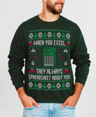 A man wearing a dark green crewneck sweatshirt with a festive holiday spreadsheet-themed graphic. The graphic features green and white snowflakes, Christmas trees, gift boxes, a spreadsheet icon, and the text 'WHEN YOU EXCEL THEY ALWAYS SPREADSHEET ABOUT YOU' in white.