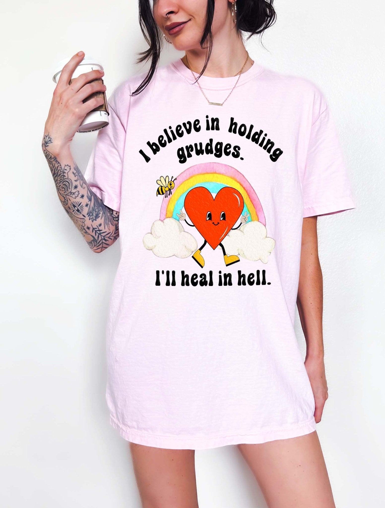 Funny sarcastic black t-shirt with retro heart and rainbow graphic reading I believe in holding grudges I’ll heal in hell