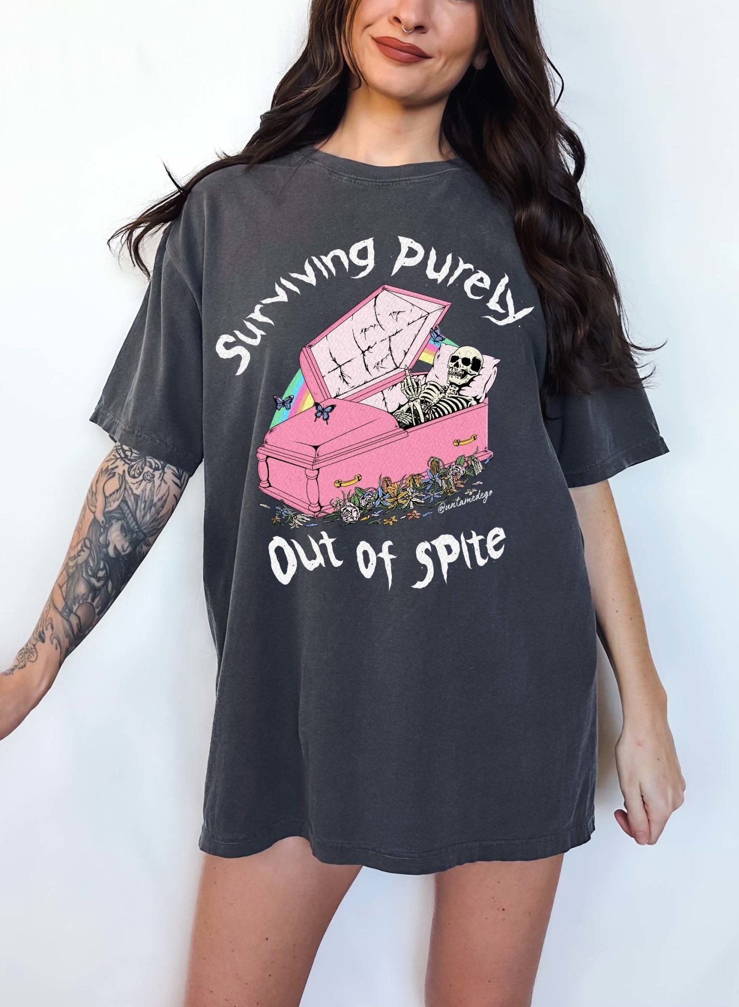 Funny graphic t-shirt with skeleton in coffin and text saying surviving purely out of spite